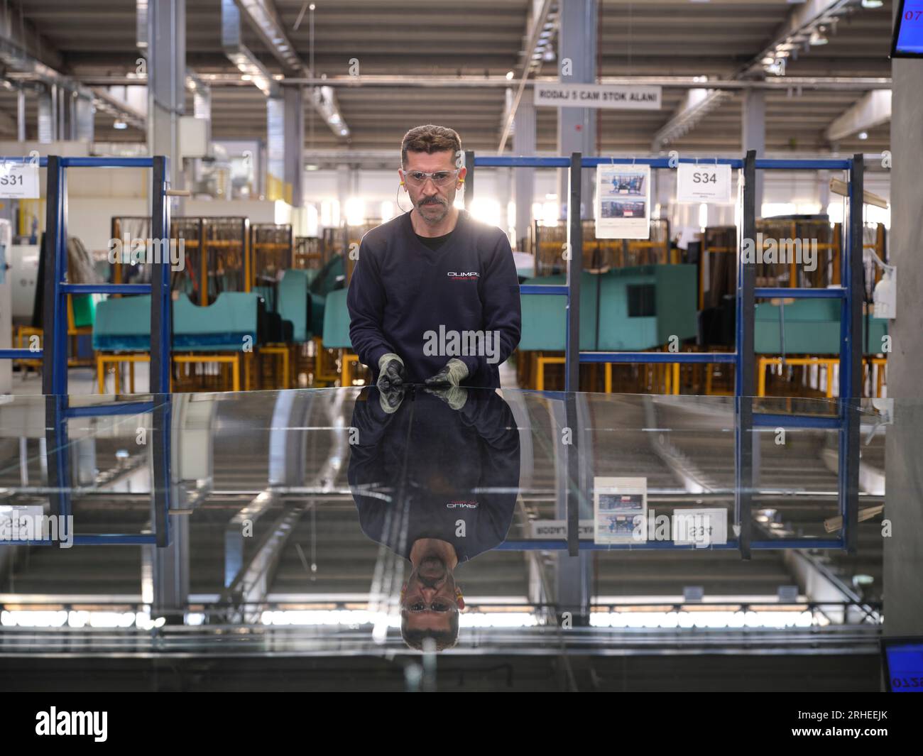 Fabbrica per la produzione di finestrini e parabrezza per auto. Lavoratore manuale che assembla finestre in PVC e finestrini per auto. Lavoratori che confezionano fogli di vetro in magazzino Foto Stock