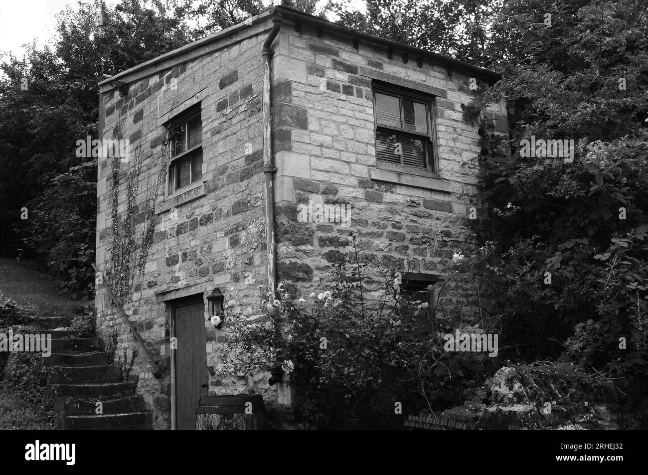 Minuscola casa in pietra calcarea con tre finestre, una porta e dei gradini che portano sul davanti Foto Stock