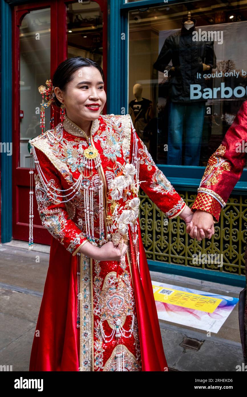 Una sposa cinese posa per foto di matrimonio in costume tradizionale all'esterno del negozio di abbigliamento di lusso Barbour a Leadenhall Market, Londra, Regno Unito. Foto Stock