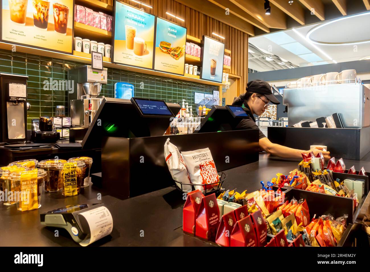 Caffè dell'aeroporto McDonalds Bahrain - lavoratrice dipendente dipendente dipendente che consegna il caffè McDonalds dietro il bancone Foto Stock