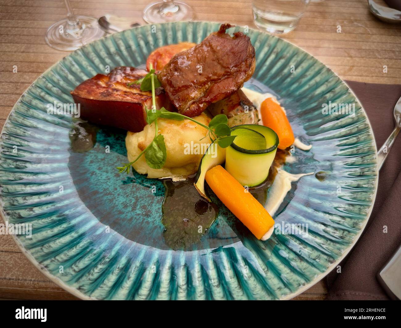 Delizie gastronomiche: Colorato pasto di maiale presso un ristorante, servito su un piatto blu Foto Stock