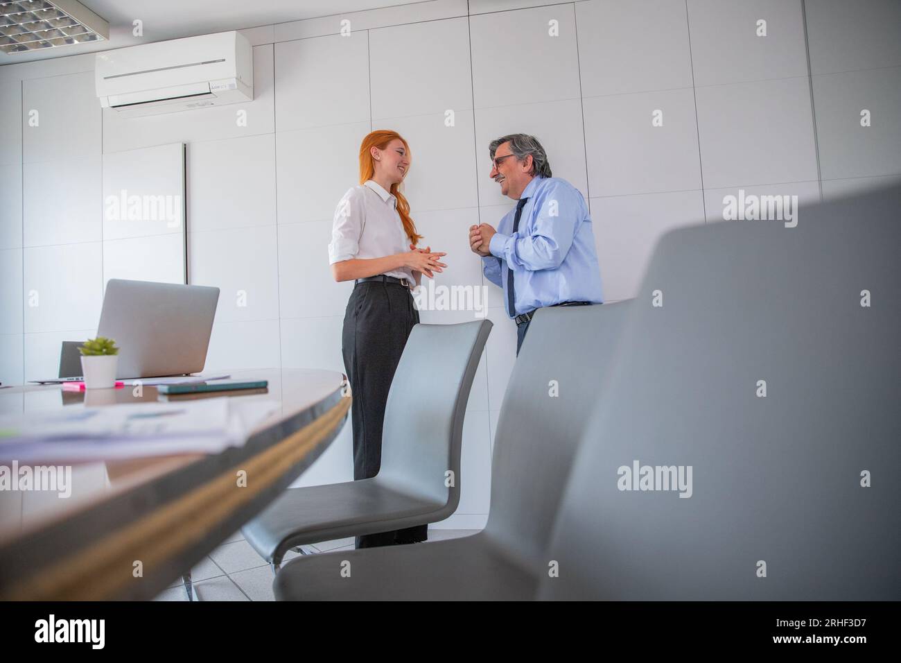 Due colleghi che conversano nella sala riunioni dell'ufficio, differenza di età Foto Stock