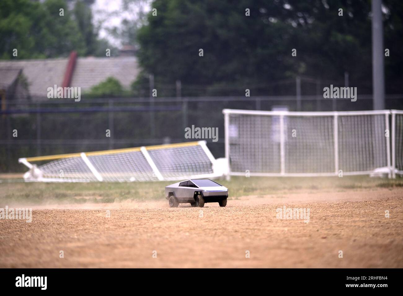 RC Cybertruck solleva la polvere su un campo da baseball, il suo percorso senza meta, il riflesso dell'incertezza, una metafora che risuona tra le sfide economiche in corso Foto Stock