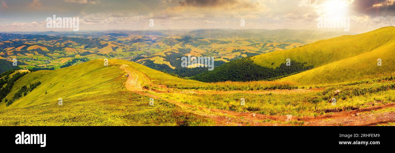 panorama montano al tramonto. curva lungo il prato in collina. valle rurale in lontananza. splendido paesaggio di campagna in serata Foto Stock