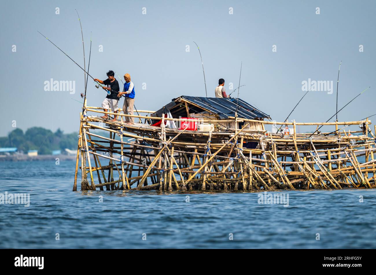 La gente del posto pesca su un altopiano di bambù che si stende sopra l'acqua. Giava, Indonesia. Foto Stock