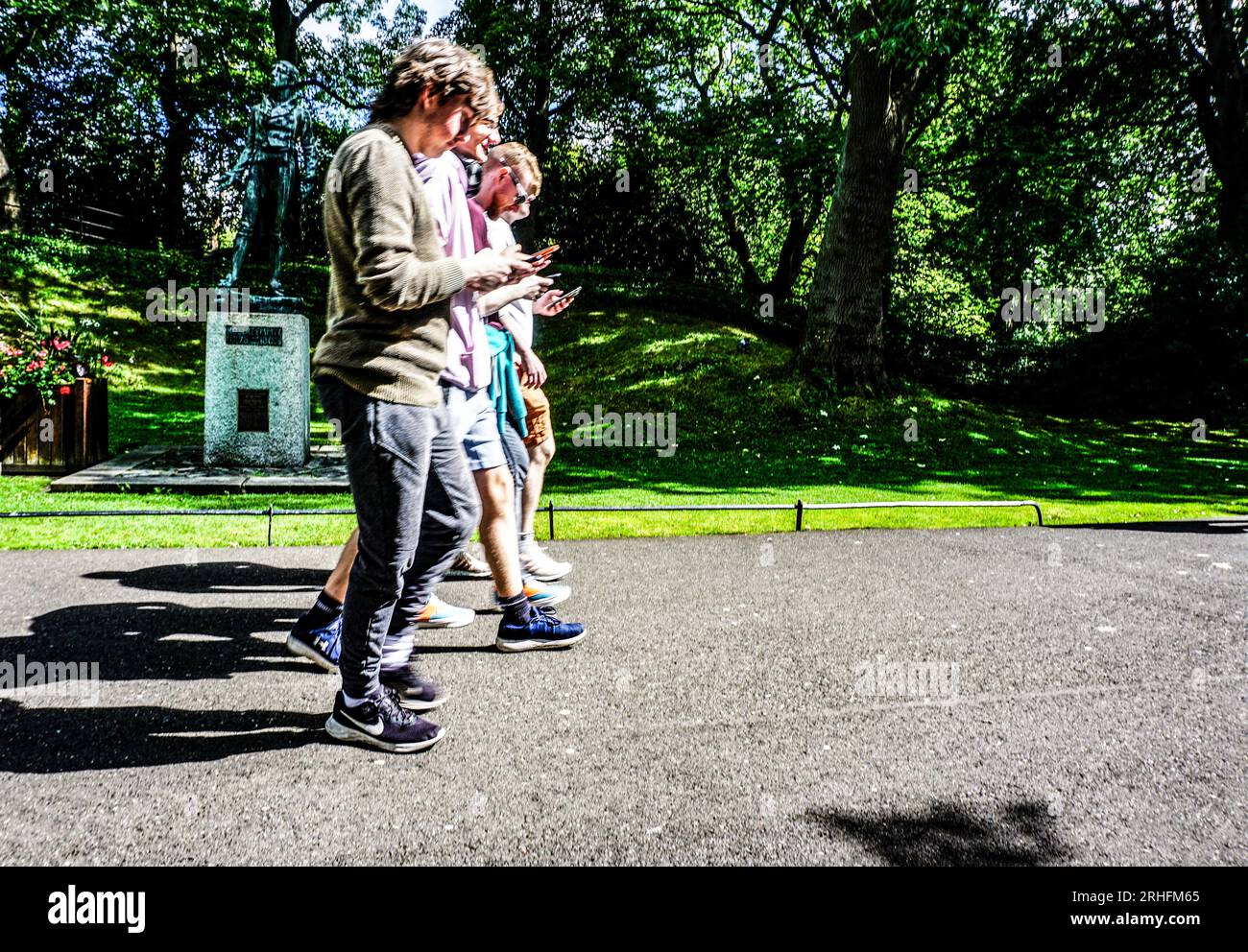 Gente che guarda i loro telefoni mentre cammina attraverso St Stephens Green a Dublino, in Irlanda. Foto Stock