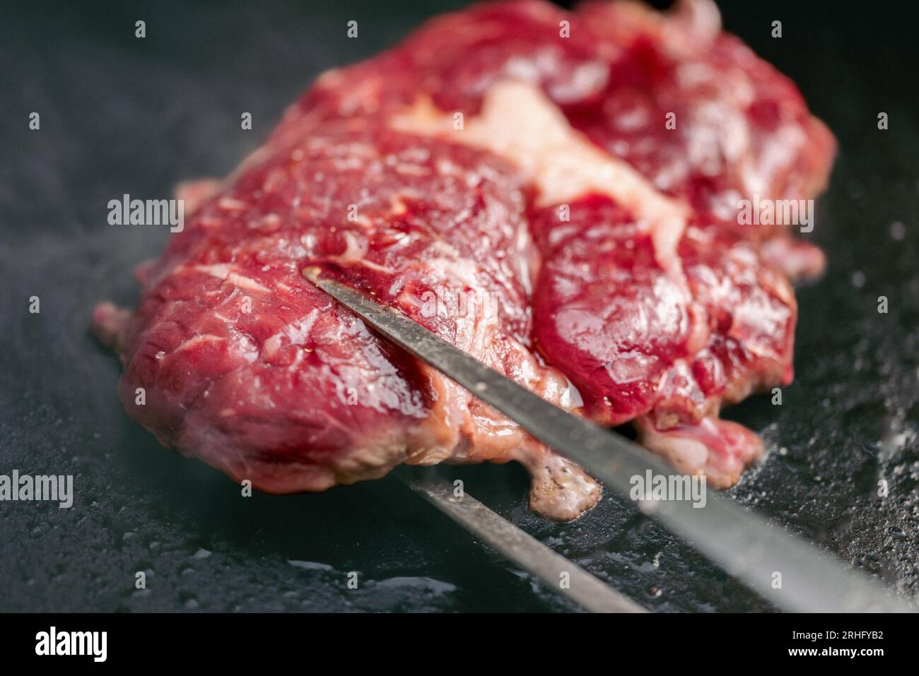 Chef che cucina bistecche su un grill con affumicato che sfrigolava il grill. Foto Stock
