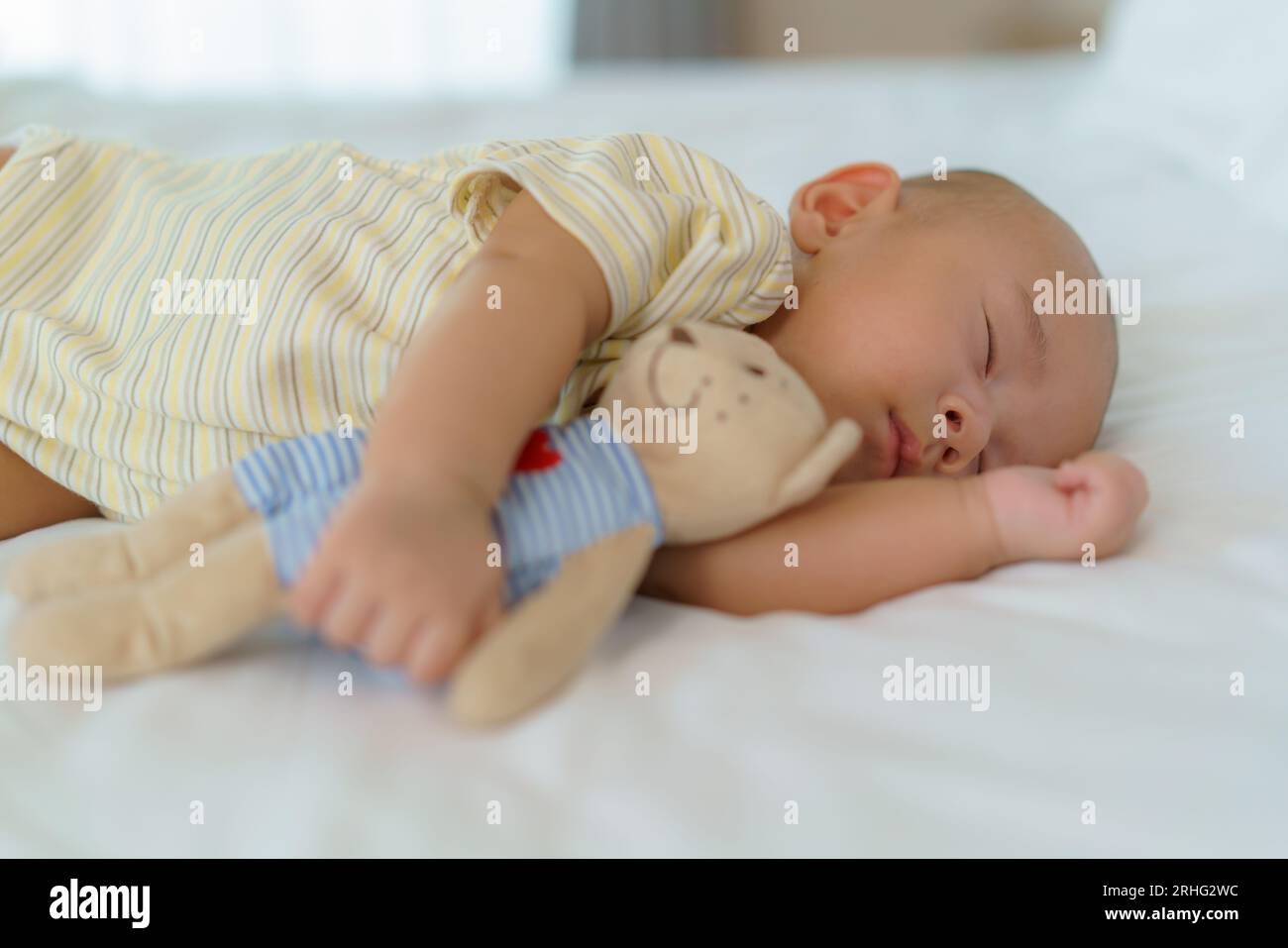 Ritratto di un neonato che dorme e abbraccia il suo orsacchiotto. nel letto nella camera da letto di casa Foto Stock