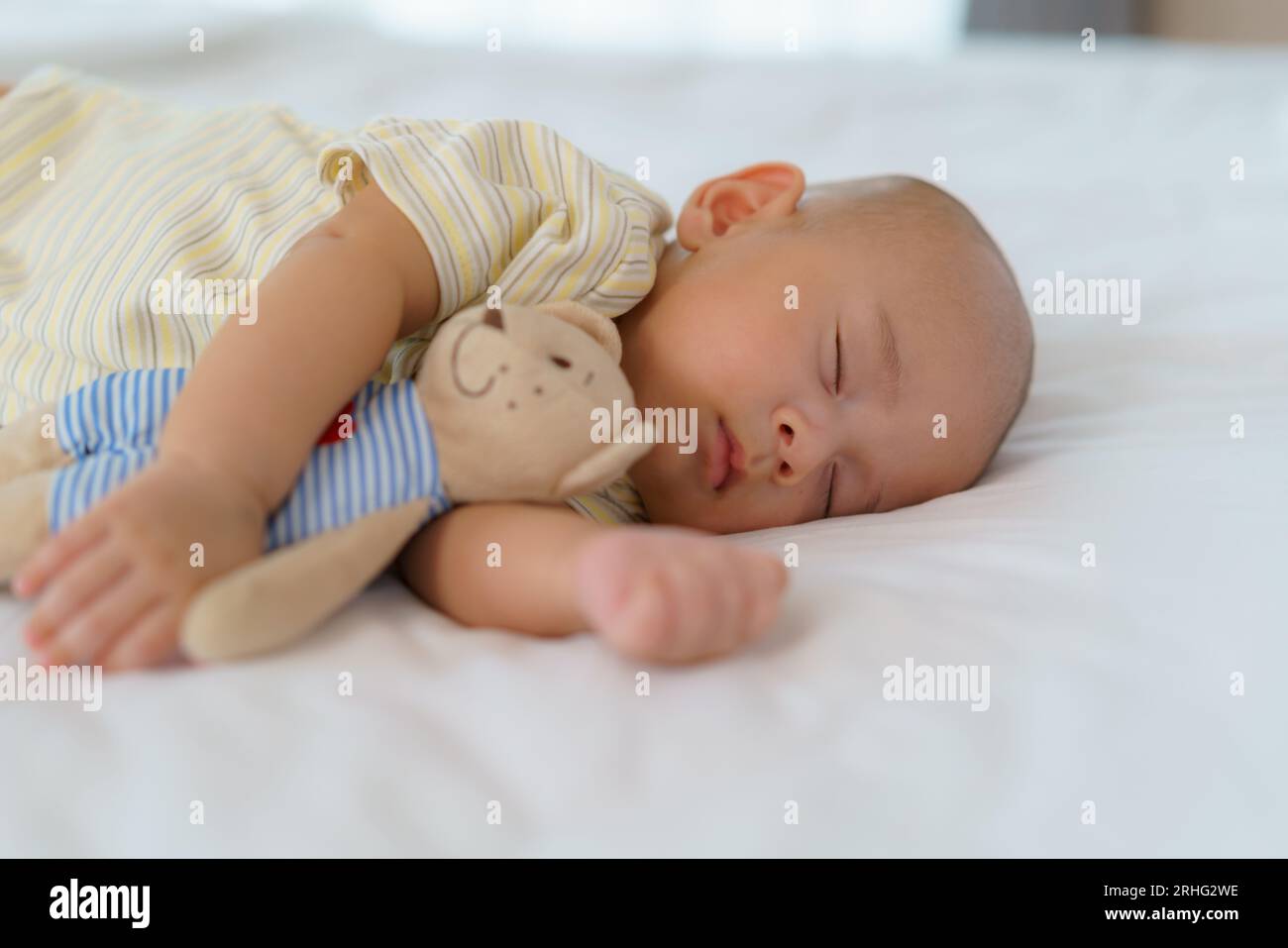 Ritratto di un neonato che dorme e abbraccia il suo orsacchiotto. nel letto nella camera da letto di casa Foto Stock