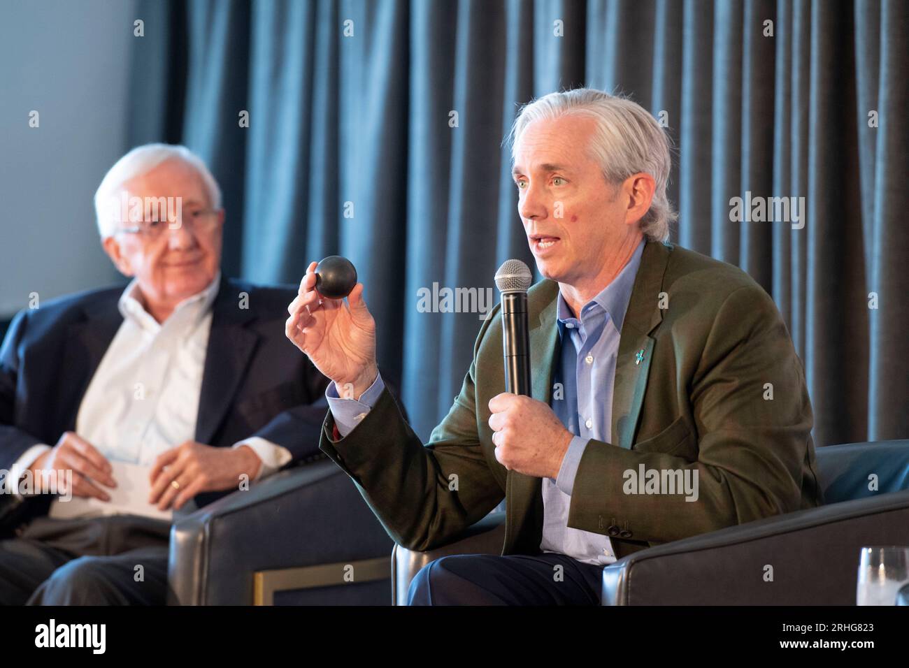 Austin Texas USA, 16 agosto 2023: Clay Sell, CEO di X-ENERGY, mostra un modello della sfera di combustibile TRISO-X che alimenterà un reattore nucleare durante una "chiacchierata a lato del fuoco" sull'importanza dello sviluppo della tecnologia nucleare e dell'energia in Texas. Il piano è incentrato su piccoli reattori modulari (SMR) di capacità di 80 megawatt che, in gruppi, alimenterebbero le esigenze delle grandi raffinerie chimiche del Texas lungo la costa del Texas. La dottoressa Dale Klein dell'Università del Texas ci guarda. ©Bob Daemmrich Foto Stock