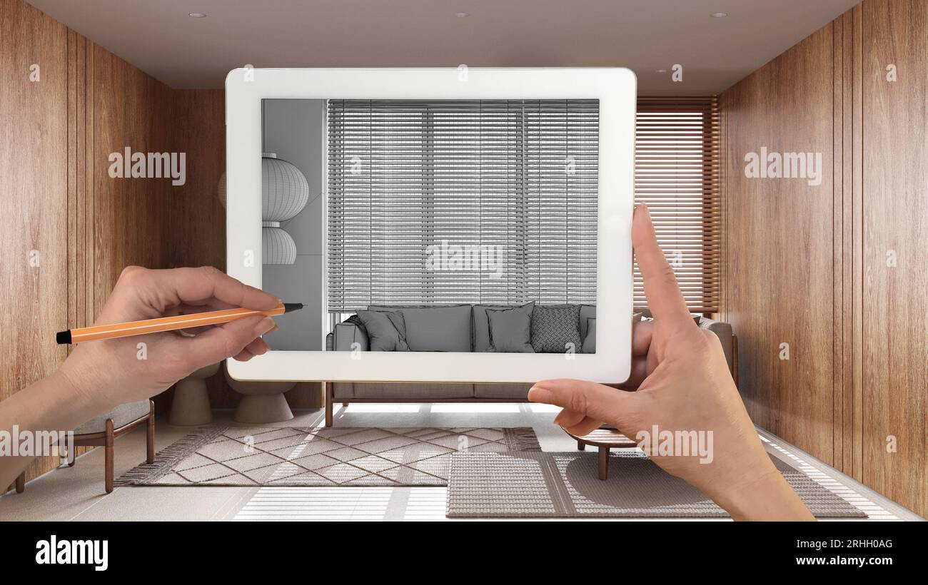 Mani che tengono e disegnano su un tablet che mostra il salotto in legno japandi con disegno CAD del divano. Interni rifiniti in vero stile architettonico sullo sfondo Foto Stock