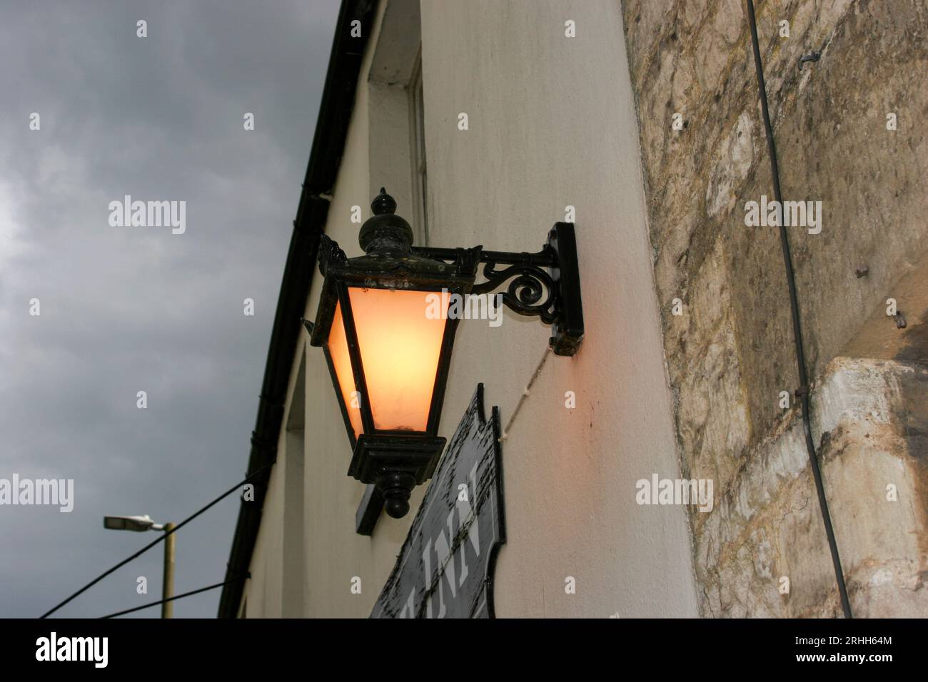 Un vecchio lampione in stile urbano sopra un edificio in pietra Cotswold. Foto Stock