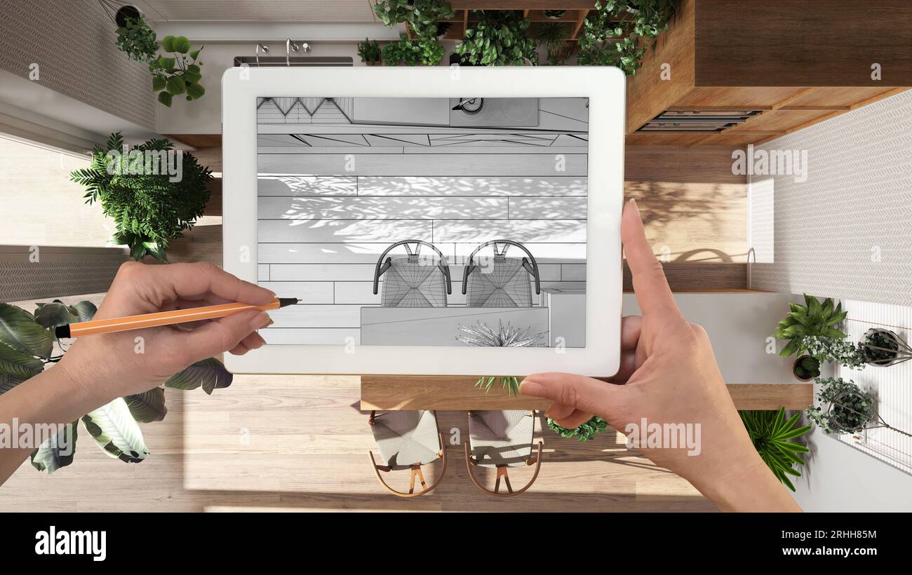 Mani che tengono e disegnano su un tablet che mostra i dettagli della cucina e della sala da pranzo schizzo CAD. Interni rifiniti sullo sfondo, design architettonico Foto Stock