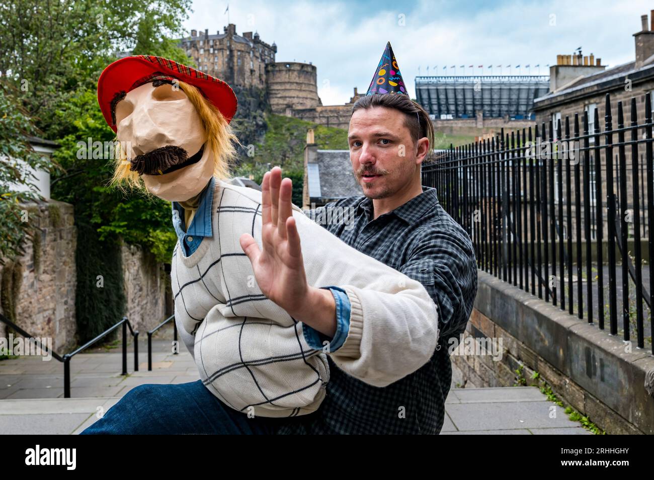 Edimburgo, Scozia, Regno Unito, 17 agosto 2023. Bill's 44th at Edinburgh Festival Fringe: Bill abbraccia tutto scozzese, indossando un cappello SEE You Jimmy Tam o'Shanter, bevendo IRN Bru con il castello di Edimburgo sullo sfondo visto dall'iconica Vennel. Questo spettacolo di burattini è stato realizzato dai burattinai di New York Dorothy James e Andy Manjuck (Andy visto qui). Crediti: Sally Anderson/Alamy Live News Foto Stock