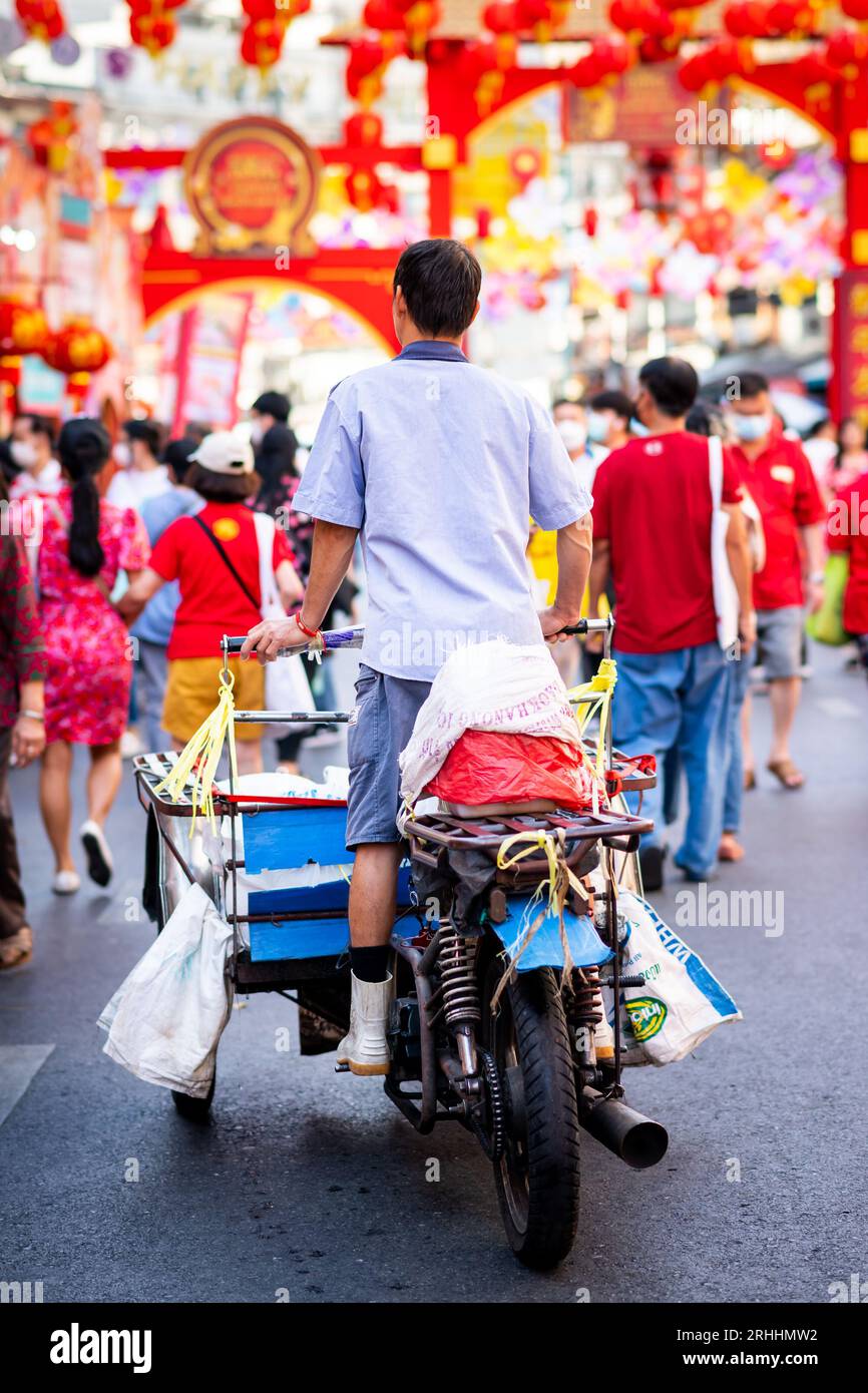 Un operaio del mercato tailandese si fa strada lungo Yaowarat Rd. Attraverso China Town, Bangkok, Thailandia. Le decorazioni provengono dalla celebrazione del capodanno cinese. Foto Stock