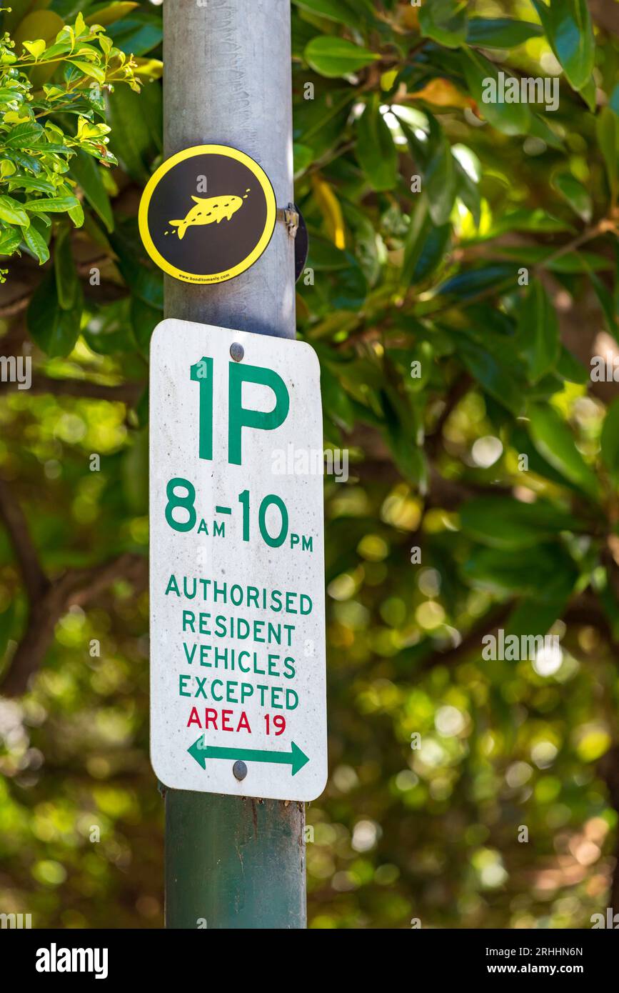 Un cartello per il parcheggio di un'ora a Elizabeth Bay, Sydney, Australia, montato sotto un piccolo pesce simbolo della passeggiata da Bondi a Manly (80 km) Foto Stock