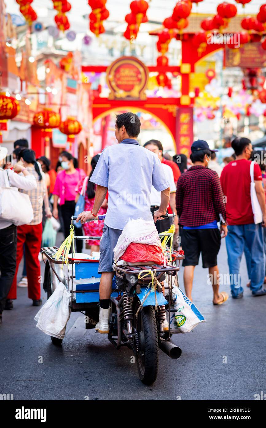 Un operaio del mercato tailandese si fa strada lungo Yaowarat Rd. Attraverso China Town, Bangkok, Thailandia. Le decorazioni provengono dalla celebrazione del capodanno cinese. Foto Stock