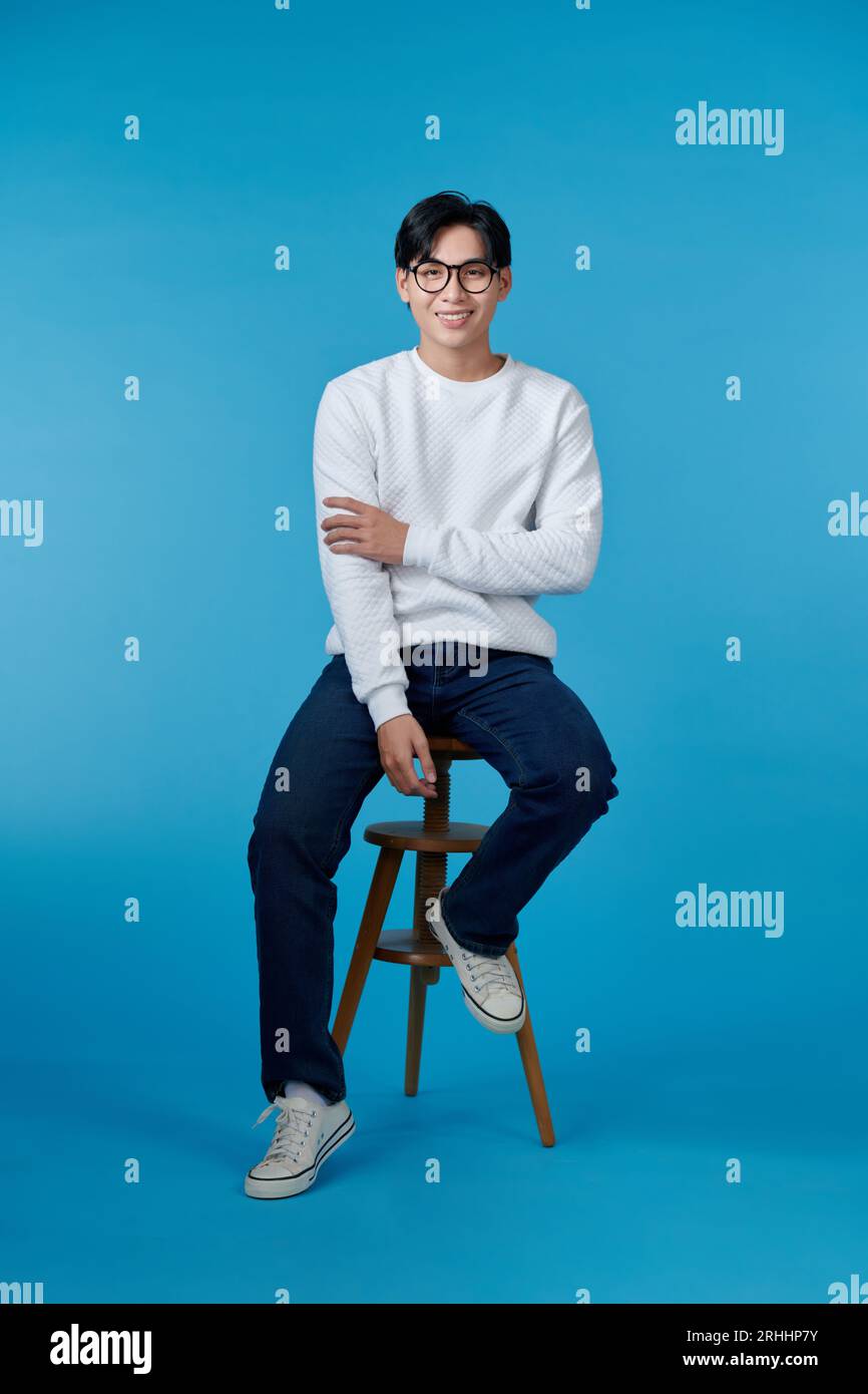 Uomo felice e casual sorridente con le mani piegate seduto su una sedia Foto Stock