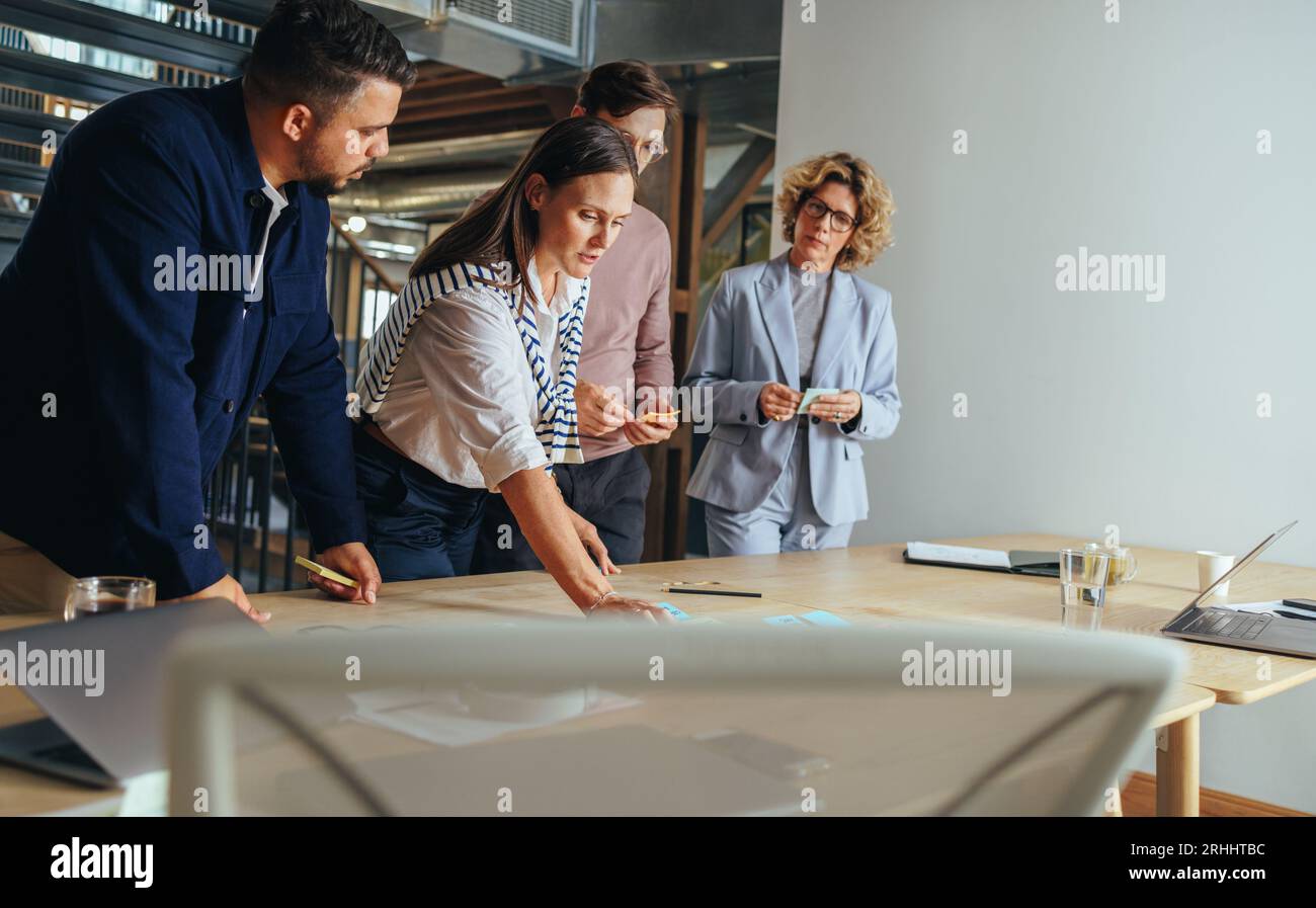 Un'agenzia pubblicitaria che ha brainstorming con appunti adesivi in ufficio. Professionisti creativi che discutono idee aziendali in una riunione. team aziendale Foto Stock