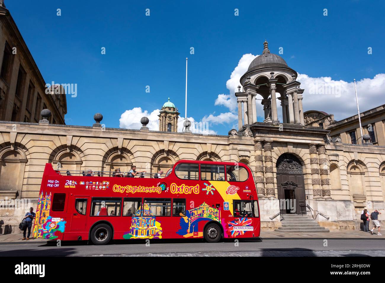 Un autobus turistico scoperto attende fuori dal Queen's College sulla famosa High Street di Oxford Foto Stock