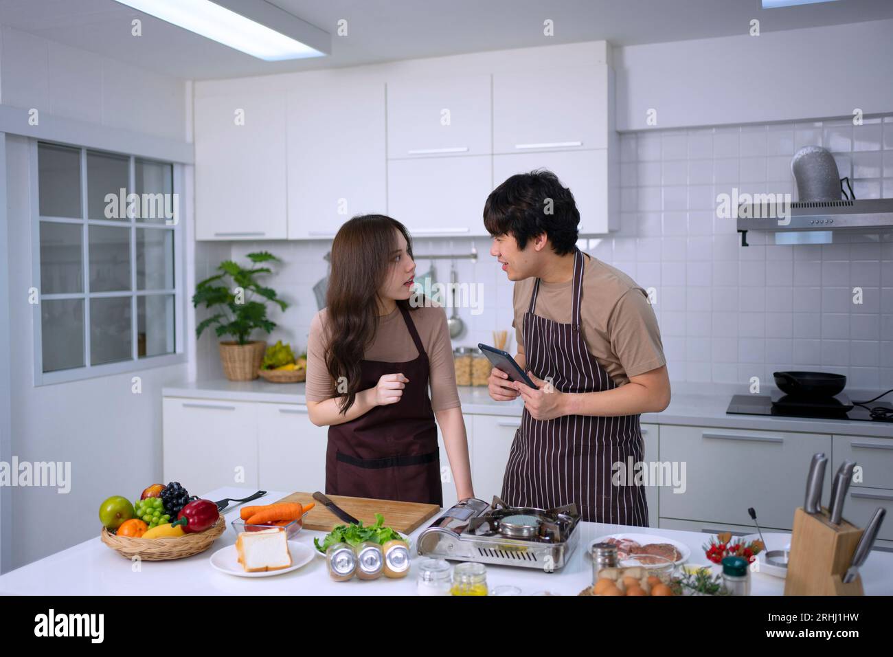 La giovane coppia sta trasmettendo in diretta in cucina. Stile di vita e attività ricreative. Foto Stock