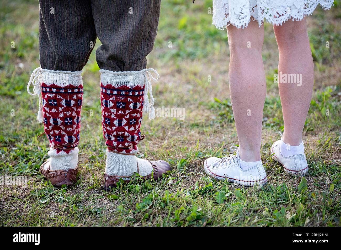 Gambe di due persone, una vestita in costume tradizionale seto, l'altra in sneakers moderne, contea di Seto, Estonia Foto Stock