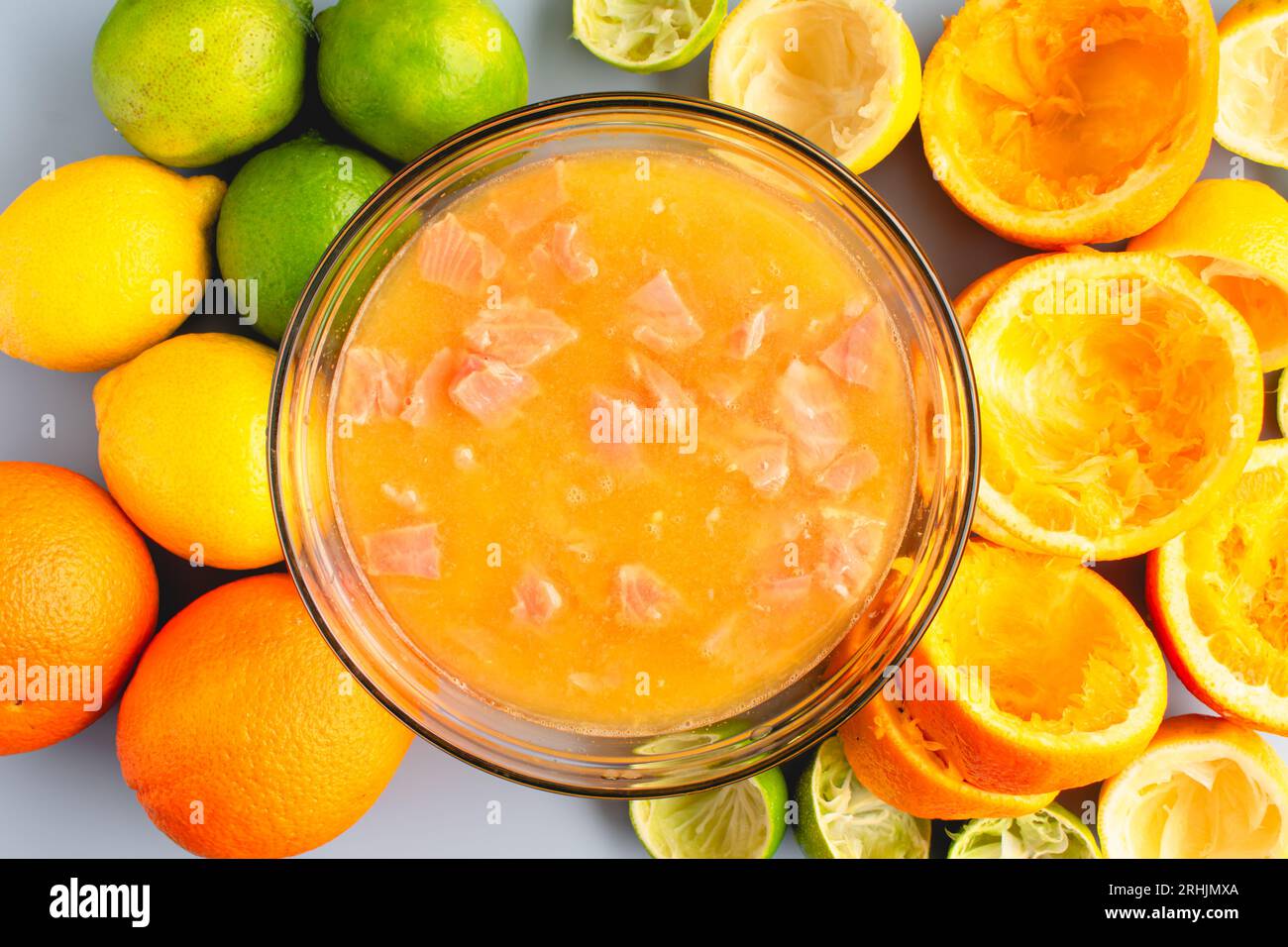 Marinare il salmone tritato in una miscela di succhi di agrumi: Preparazione del ceviche marinando il salmone crudo in succhi di arancia, limone e lime Foto Stock