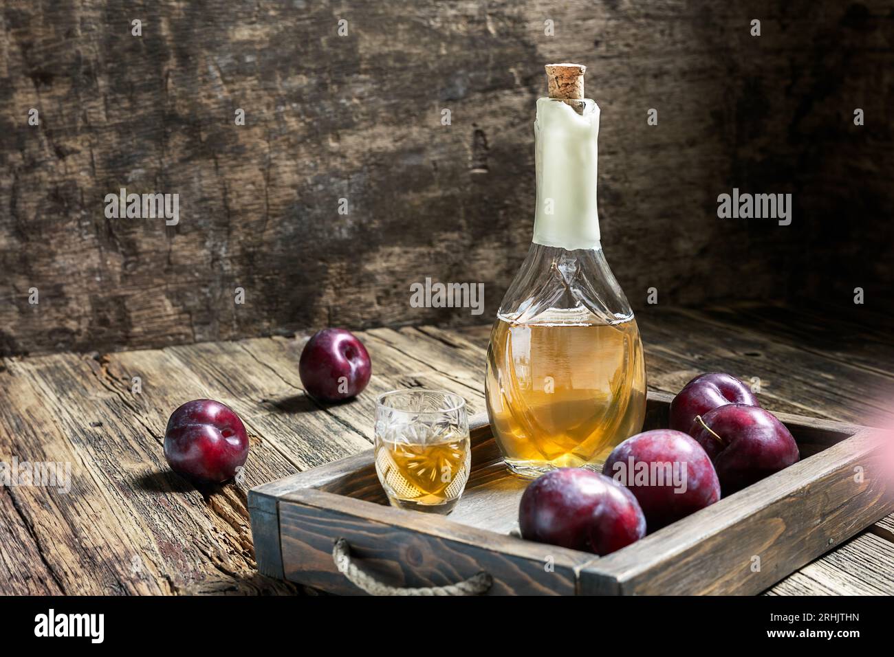 Tradizionale brandy di prugna balcanica - rakija o rakia slivovica in bottiglia, una wineglass con sljivovica e prugne fresche su sfondo di legno scuro Foto Stock