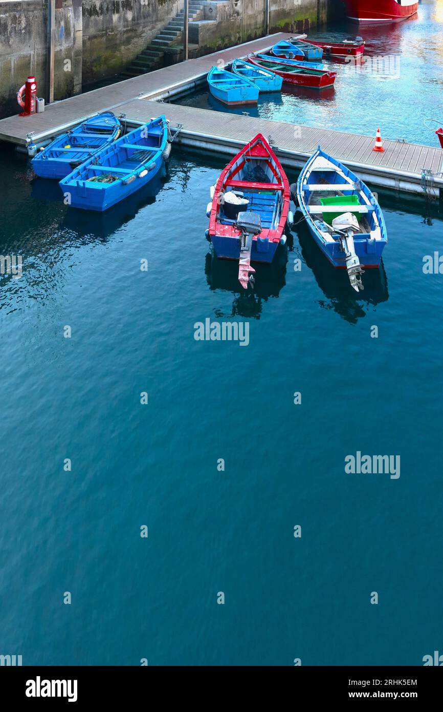 Barche da pesca rosse e blu ormeggiate nel porto marittimo di Luarca nelle Asturie, in Spagna. Foto Stock