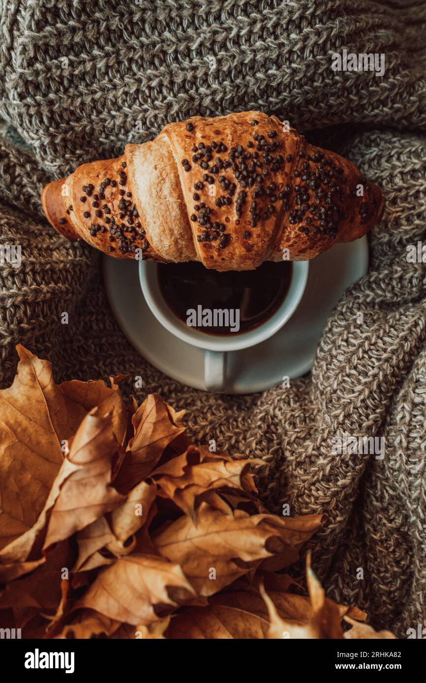 Una tazza di caffè nero mattutino con un croissant al cioccolato francese. Pasto delizioso. Estetica nei dettagli. Tonalità accoglienti beige e marrone Foto Stock