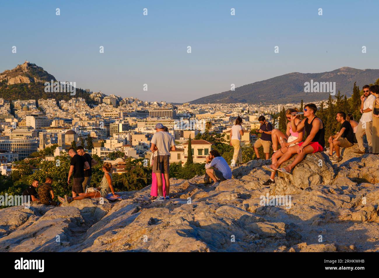 Atene, GR - 29 luglio 2023: Persone che guardano il tramonto sulla collina di Areopago Foto Stock