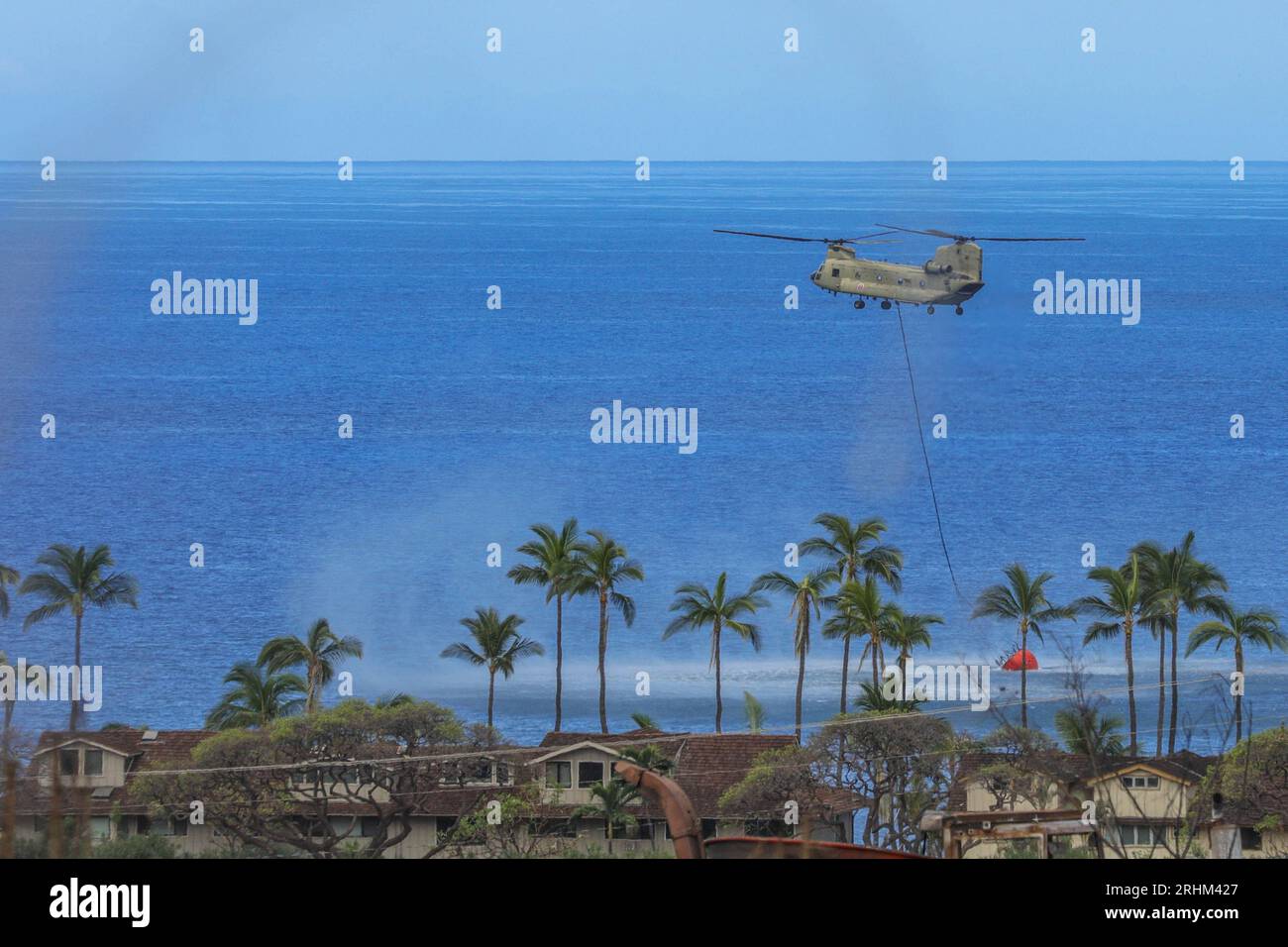 Lahaina, Maui, il 16 agosto 2023. Un CH-47 Chinook dell'esercito statunitense riempie un secchio di acqua di mare per cadere intorno al perimetro dell'area colpita dagli incendi a Lahaina, Maui, il 16 agosto 2023. I membri della Joint Task Force 50 (JTF-50) dell'esercito delle Hawaii e dell'Air National Guard, U.S. Army Active Duty and Reserve stanno attivamente sostenendo le autorità della contea di Maui per fornire sicurezza e sicurezza immediate, e benessere a coloro che sono stati colpiti dagli incendi per garantire un sostegno costante alla comunità di Maui e ai soccorritori. Foto di SPC. Tonia Ciancanelli/U.S. Guardia nazionale dell'esercito/UPI Foto Stock