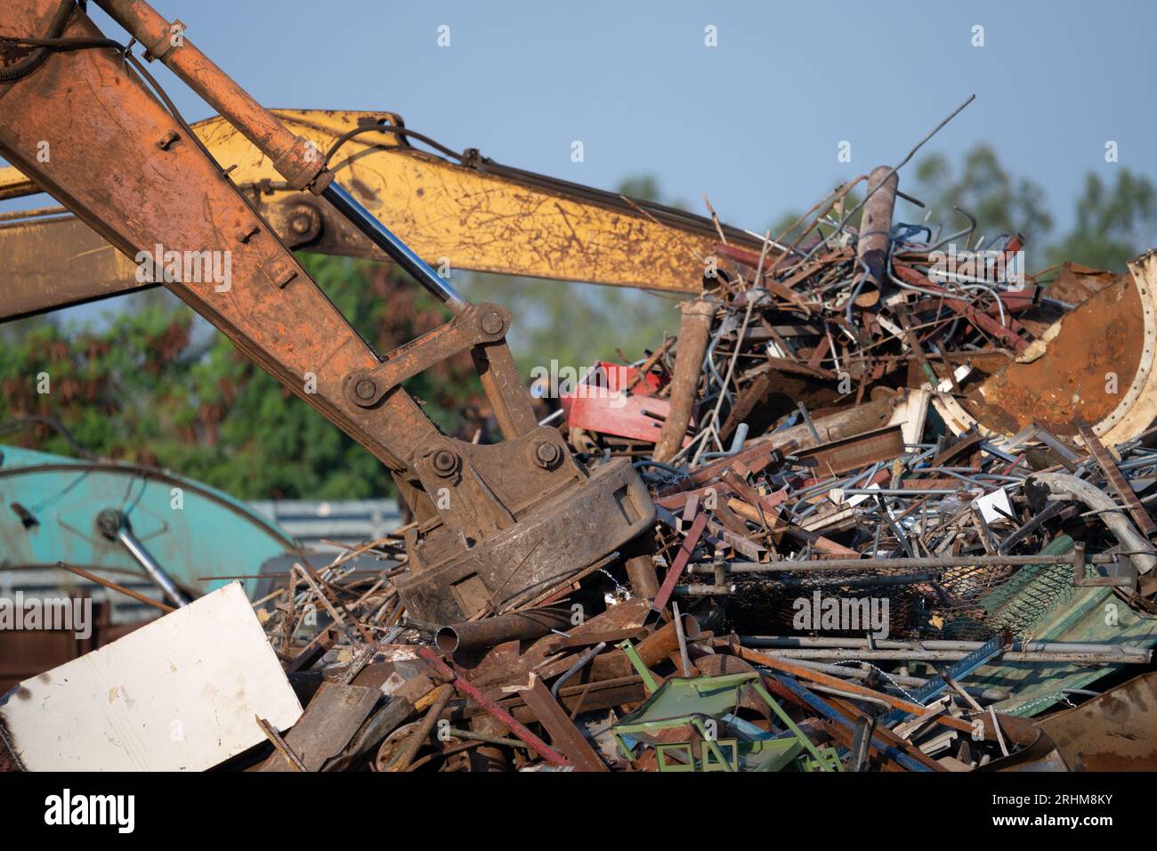 Il magnete dell'escavatore solleva i rottami d'acciaio dal cumulo di materiali riciclati presso il deposito di rottami in un impianto di riciclaggio. Escavatore con aspiratore elettromagnetico Foto Stock
