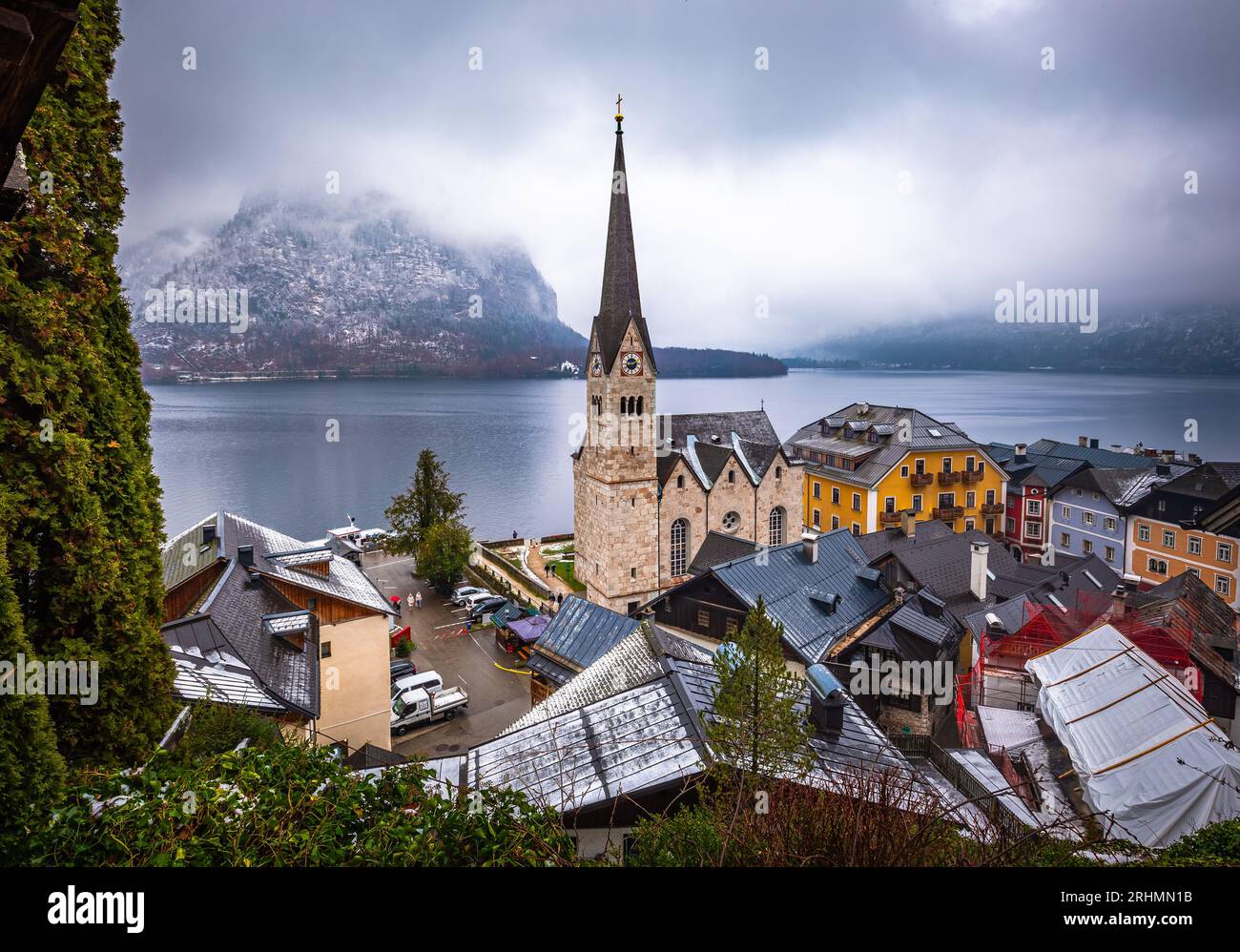 Hallstatt, Austria - la famosa Hallstatt, la città sul lago protetta dall'UNESCO con la chiesa luterana di Hallstatt in una fredda giornata di nebbia con la selce innevata Foto Stock