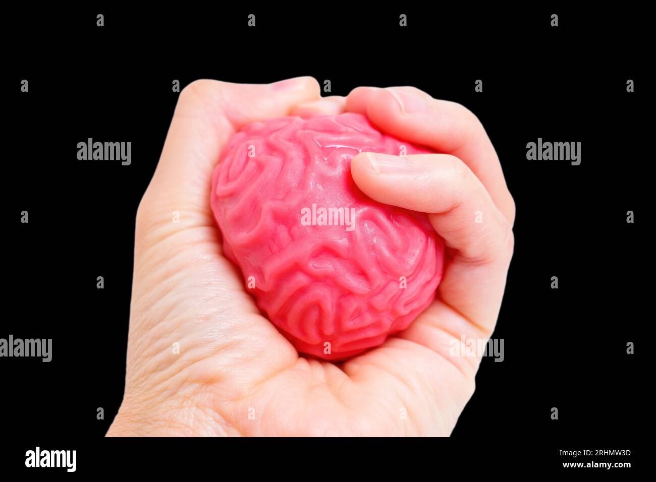 Schiacciare con decisione un modello di cervello umano a forma di gelatina e flessibile isolato su nero. Pressione ambientale professionale, intenso sforzo mentale, sfide di lavoro Foto Stock