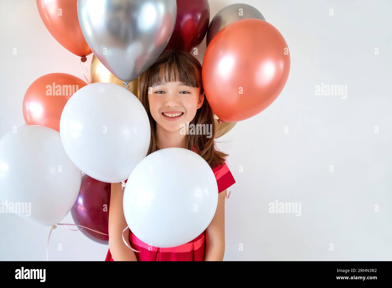Una bambina di dieci anni circondata da palloncini colorati Foto Stock