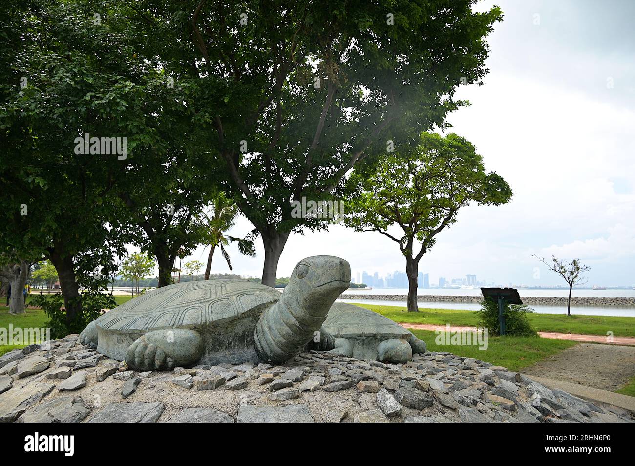 Sculture in pietra di tartarughe sull'isola di Kusu con la spiaggia e lo skyline del CBD in lontananza, situate a circa 5,6 km a sud dell'isola principale Foto Stock