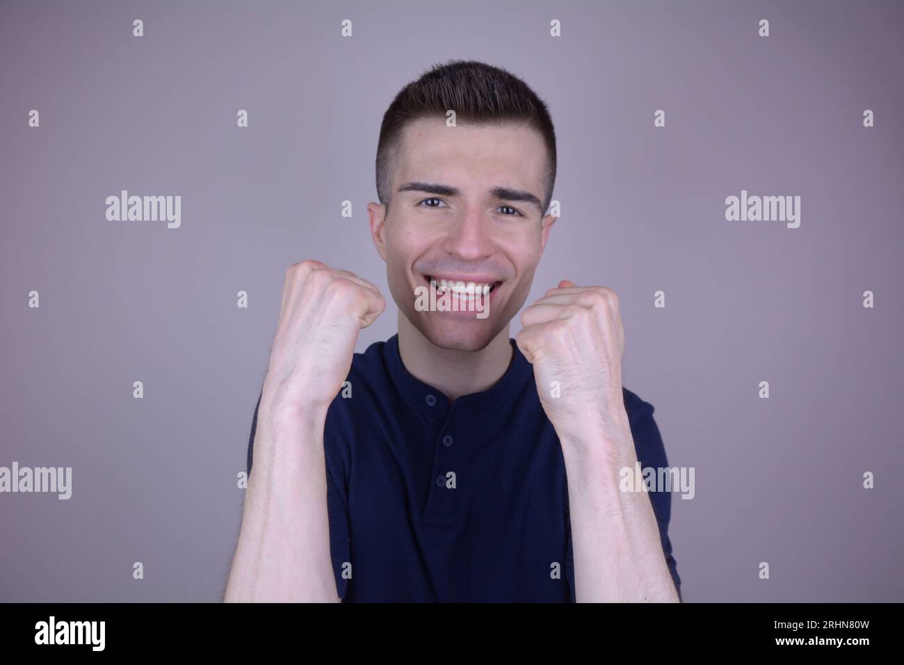 Joyful Caucasian Man celebra la vittoria con Raised Fists su sfondo isolato Foto Stock