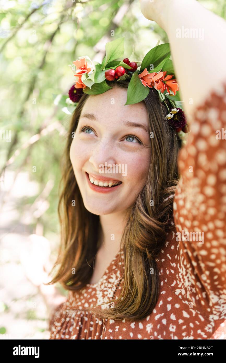 Una donna con una corona di fiori che afferra un ramo d'albero Foto Stock