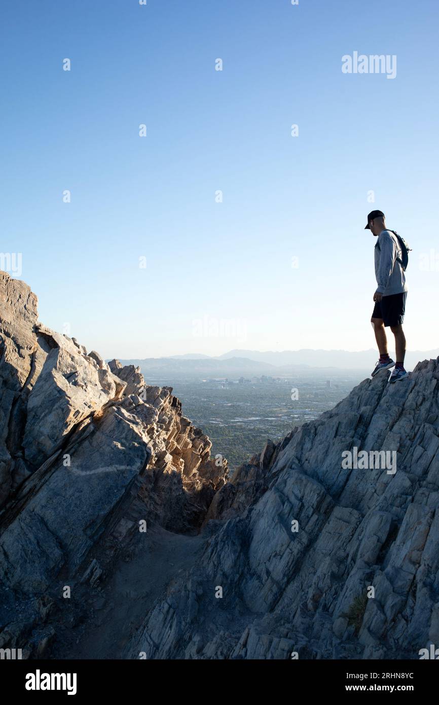 Atletico maschile in piedi su rocce che si affacciano sulla verticale della città Foto Stock