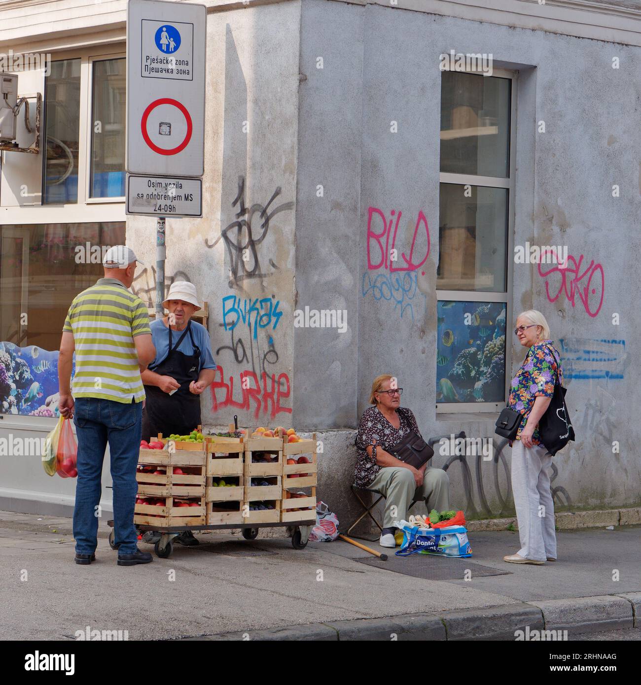 Gente che vende frutta e verdura su un marciapiede in un angolo di strada con graffiti nella città di Sarajevo, Bosnia ed Erzegovina, 18 agosto 2023. Foto Stock