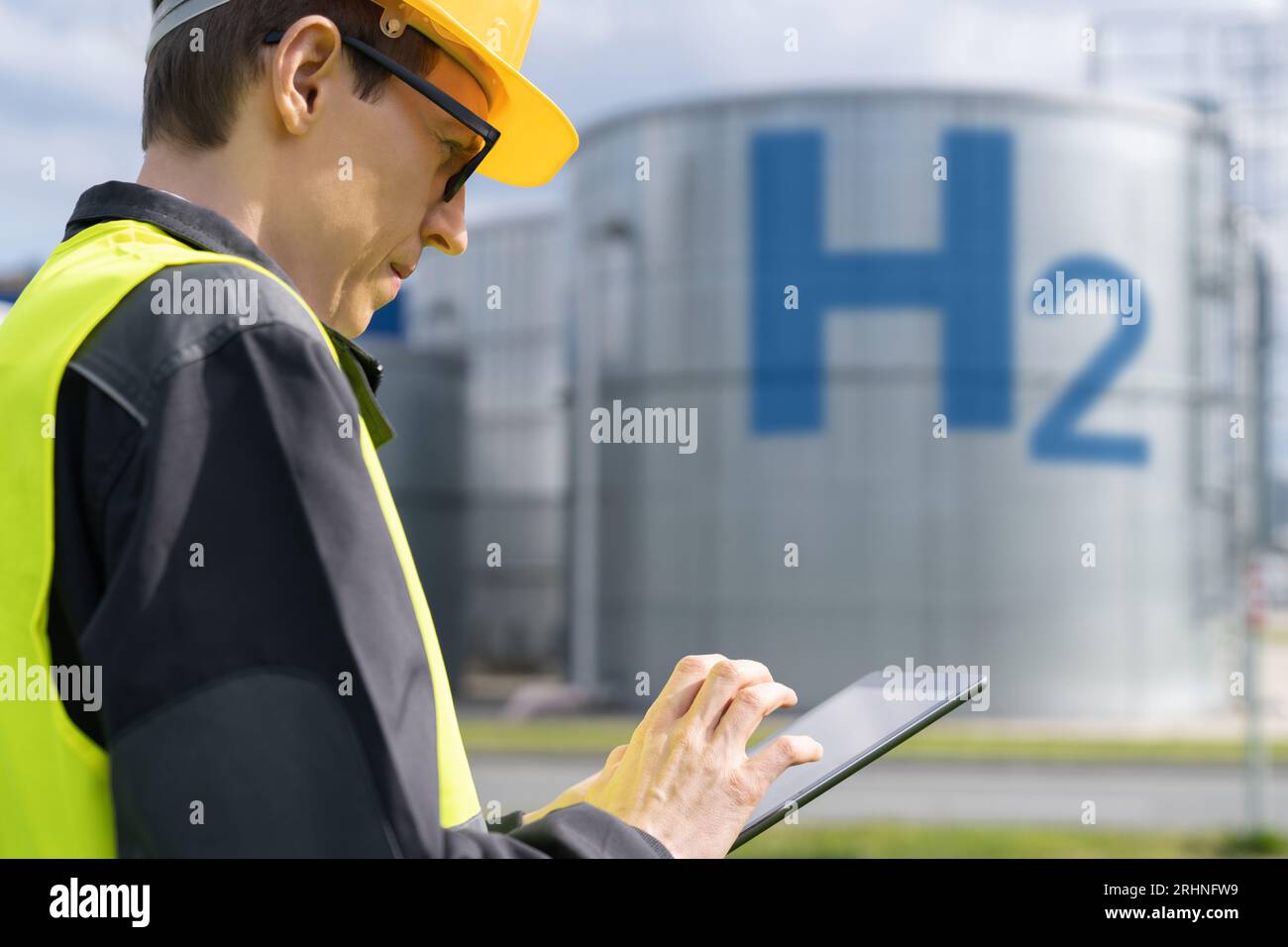 Ingegnere con un tablet su un background di fabbrica di idrogeno. Foto Stock