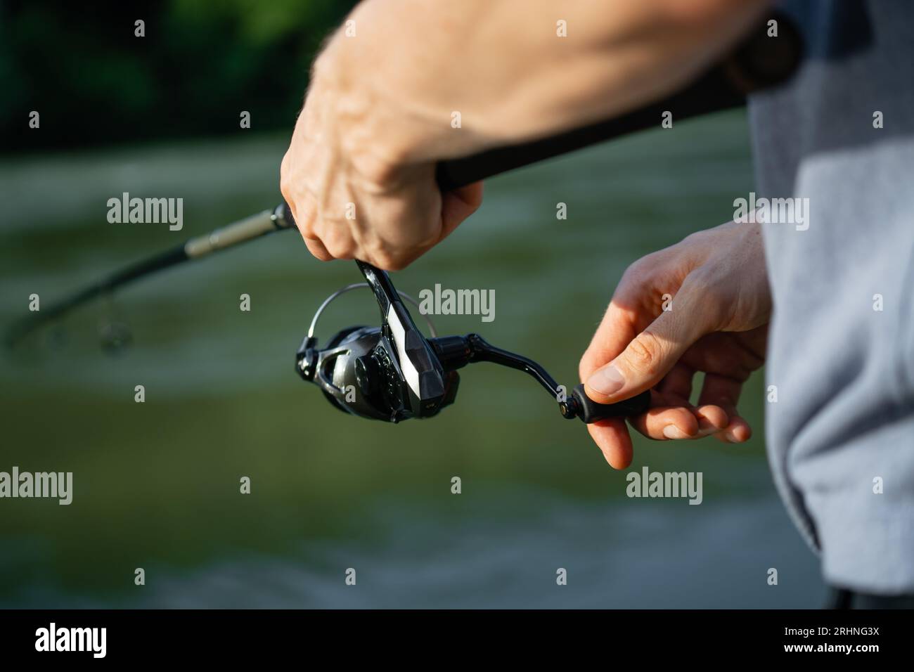 Primo piano delle mani di un pescatore con una canna da pesca Foto Stock