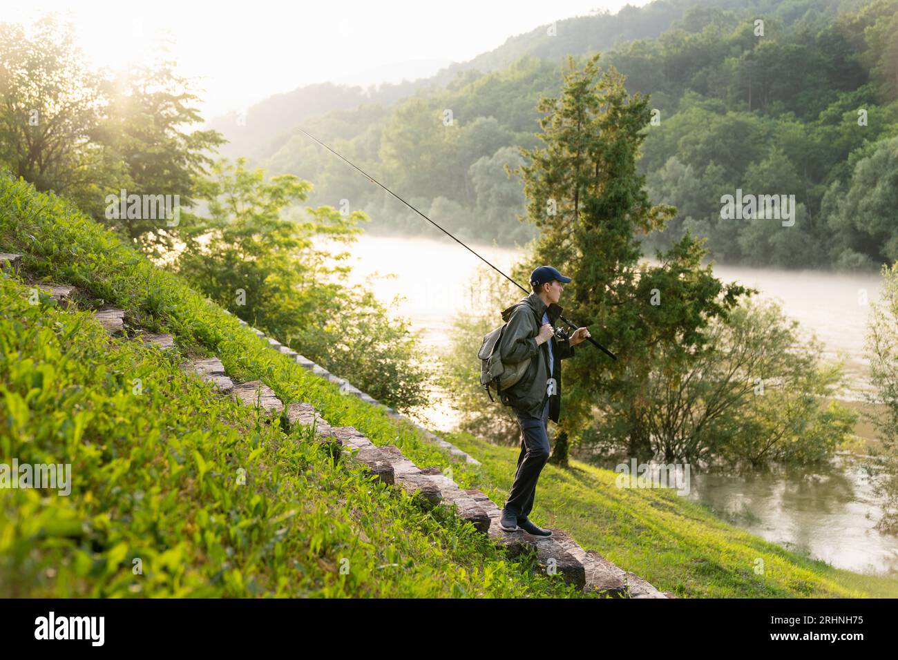 Uomo che pesca sul fiume di montagna. Foto Stock