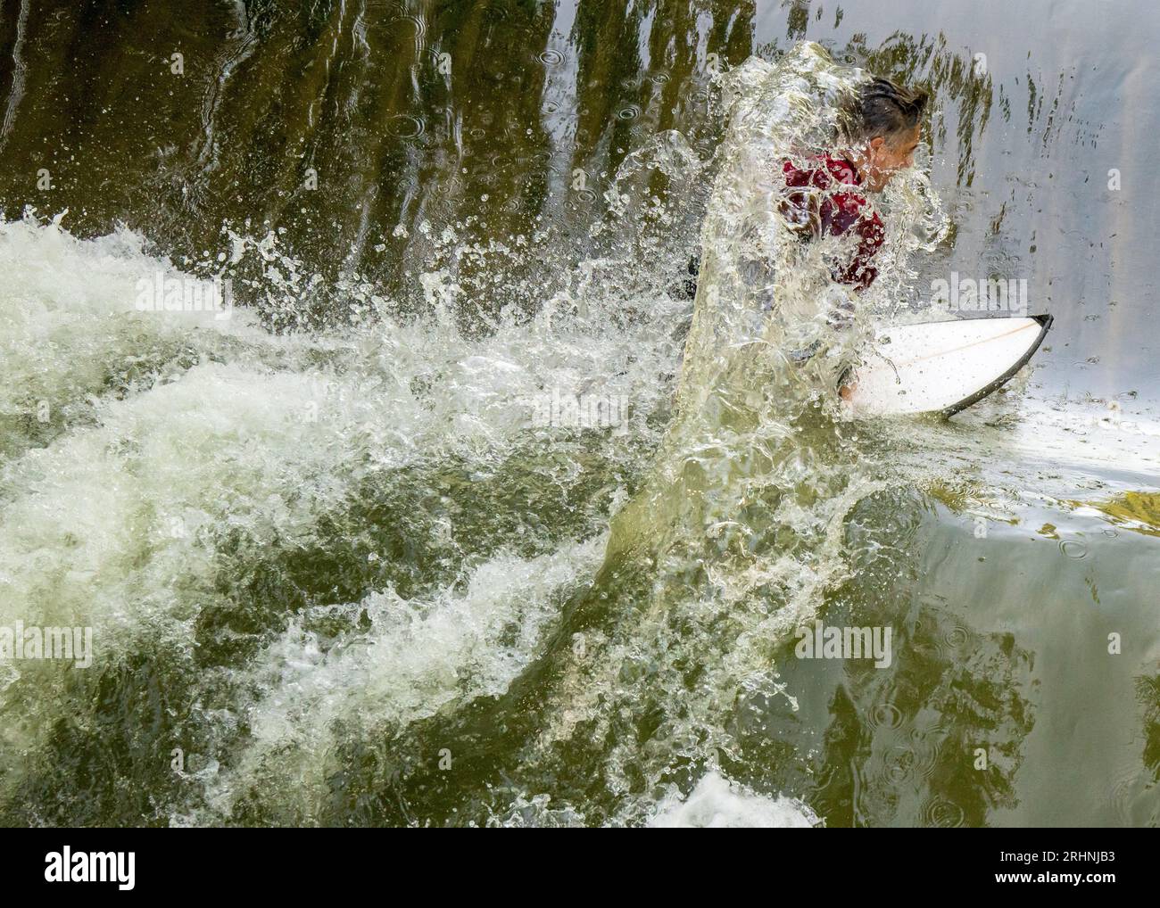 18 agosto 2023, Baviera, Monaco: Un surfista cavalca la sua tavola sull'onda di surf Floßlände vicino al fiume Isar, nel sud della capitale bavarese. Foto: Peter Kneffel/dpa Foto Stock