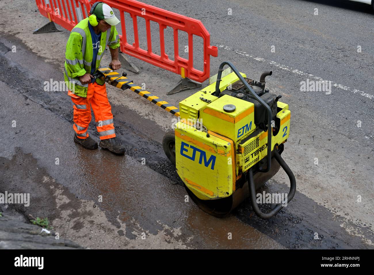 Compattazione con rullo vibrante finitura trincea tagliata su strada per condotti in fibra ottica in aggiornamento comunicazioni, Regno Unito Foto Stock