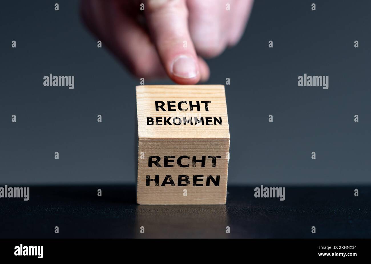 La mano ruota il cubo di legno e cambia l'espressione tedesca "recht haben" (sii giusto) in "recht bekommen" (ottenere giustizia). Simbolo per il detto tedesco. Foto Stock