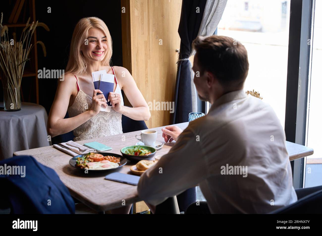 Una donna eccitata che tiene e mostra al suo fidanzato i biglietti per l'aereo Foto Stock