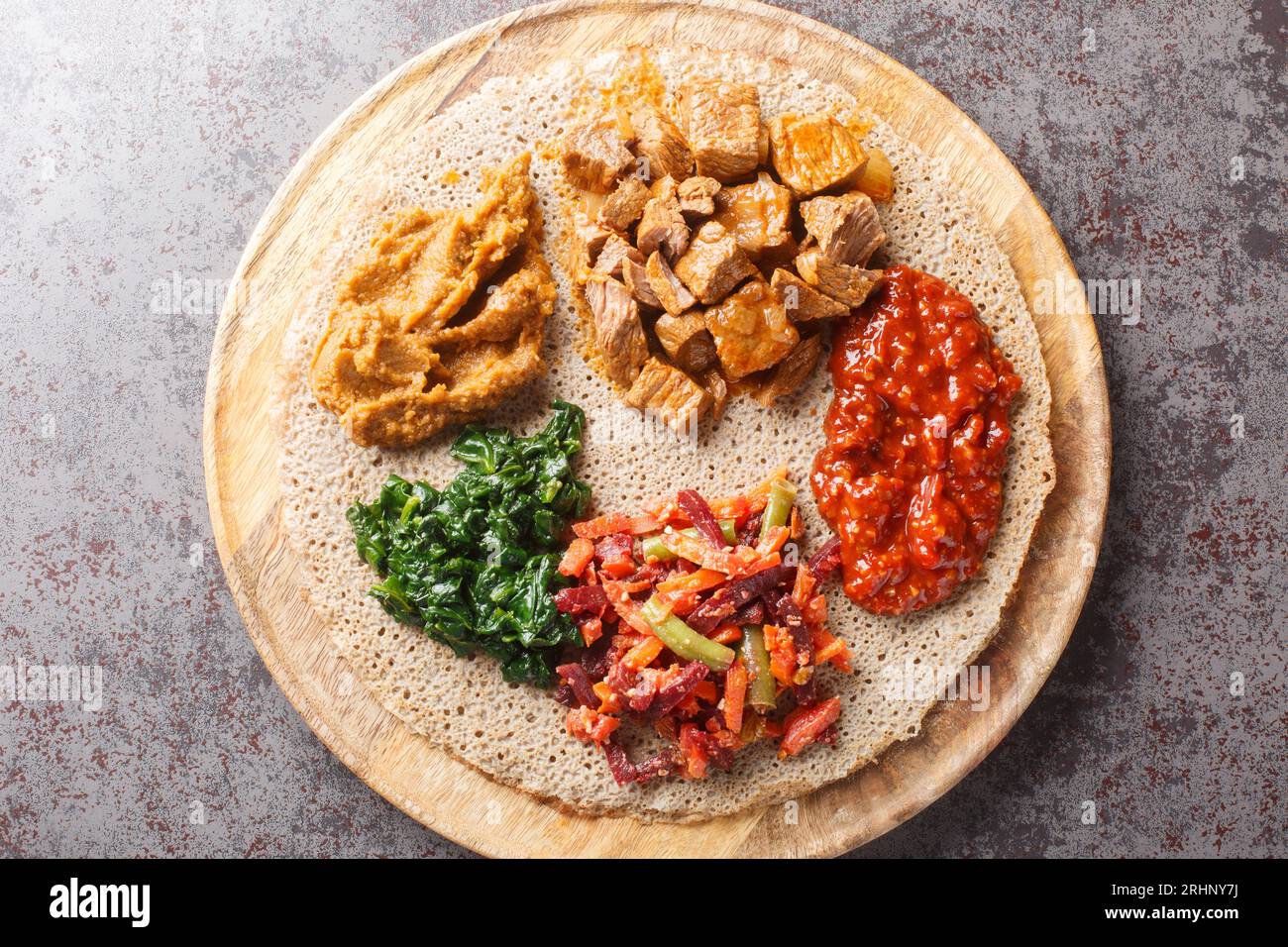 L'Injera è una focaccia a lievito naturale fatta con farina di teff servita con ripieno da vicino sulla tavola di legno sul tavolo. Vista superiore orizzontale dall'alto Foto Stock