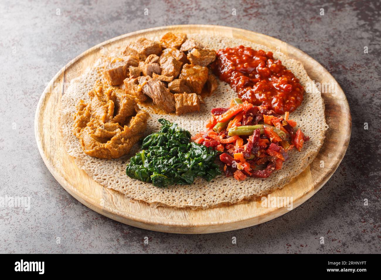L'Injera è una focaccia a lievito naturale fatta con farina di teff servita con ripieno da vicino sulla tavola di legno sul tavolo. Orizzontale Foto Stock